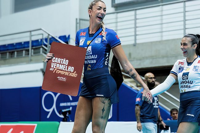Atletas do time feminino de vôlei do Minas Tenis Clube entram em quadra segurando o Cartão Vermelho ao Feminicídio